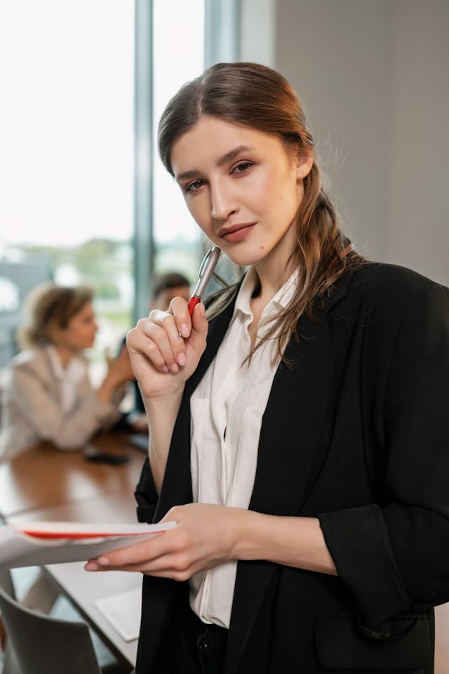 Business professional holding documents and a pen, representing confident oversight and coordination of vendor relationships.