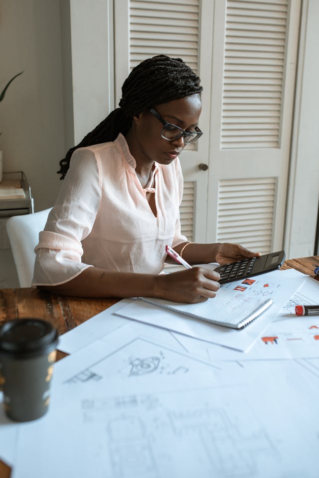 Architect reviewing building plans and calculations at a desk, representing effective architectural oversight.