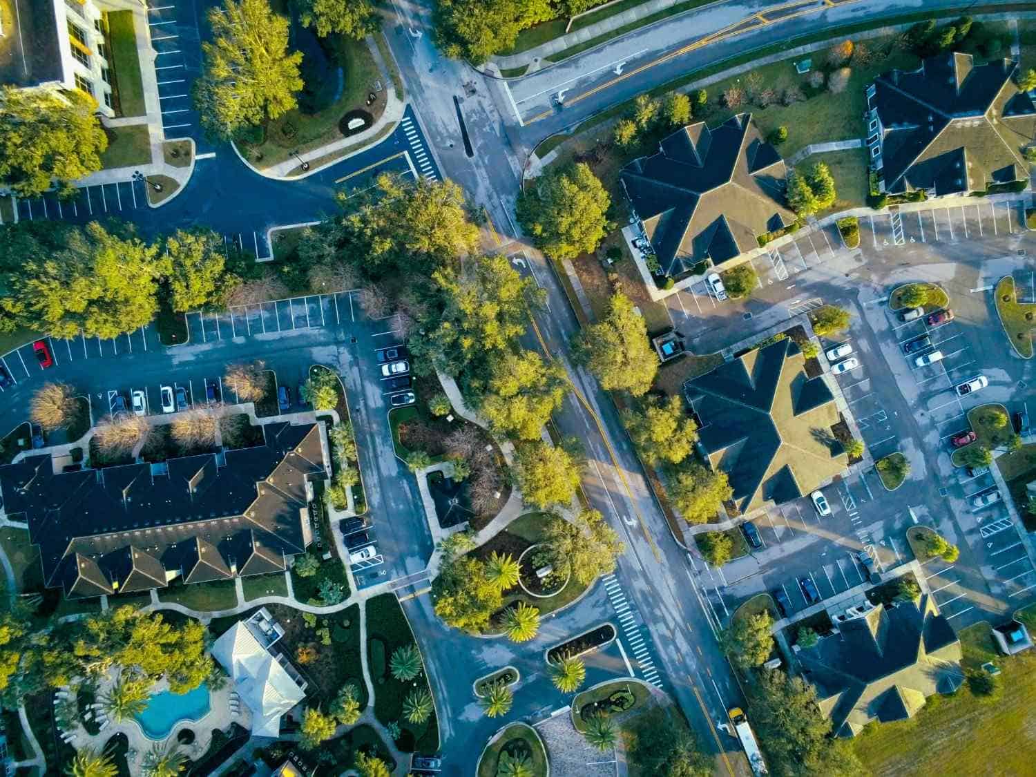 An aerial, top-down view of a well-maintained residential community in Lake Oswego, Oregon, featuring organized parking lots, green landscaping, pristine roadways, and residential buildings managed by professional HOA services.