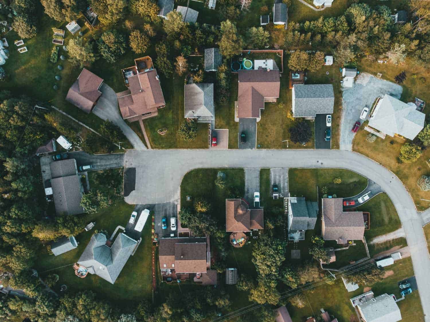 An overhead aerial view of a quiet cul-de-sac and residential neighborhood in Lincoln City, Oregon, showing neatly arranged houses, driveways, and lush green lawns overseen by professional HOA management.
