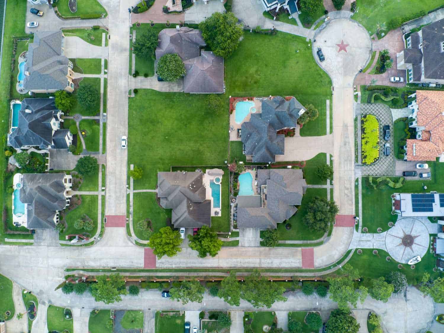An overhead, top-down aerial view of a clean and spacious suburban neighborhood in Salem, Oregon, showcasing sprawling green lawns, private swimming pools, and pristine streets under professional HOA management.